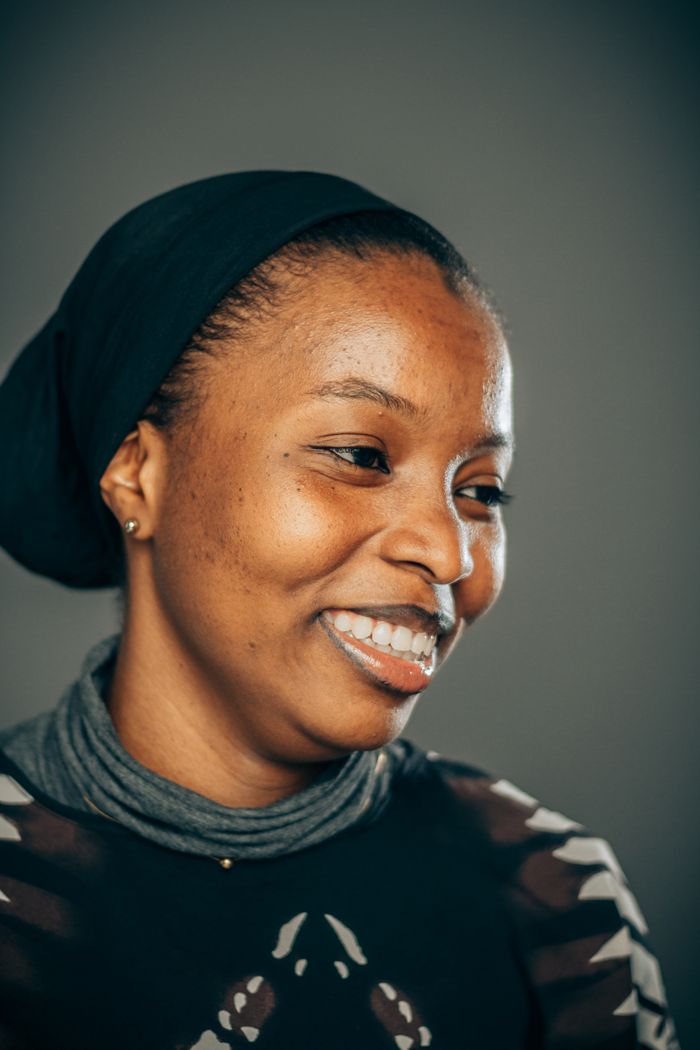 Close-up portrait of a smiling woman wearing a headscarf, exuding warmth and confidence.